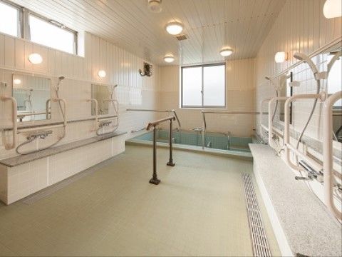 広い洗い場が設けられた大浴場である。清潔感のある白を基調とした両サイドの壁には、鏡やシャワーが複数設置されている。
