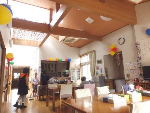 食堂には日の光が差し込み、明るく開放感がある。数名の入居者様とスタッフが、清掃や台所仕事をしている。