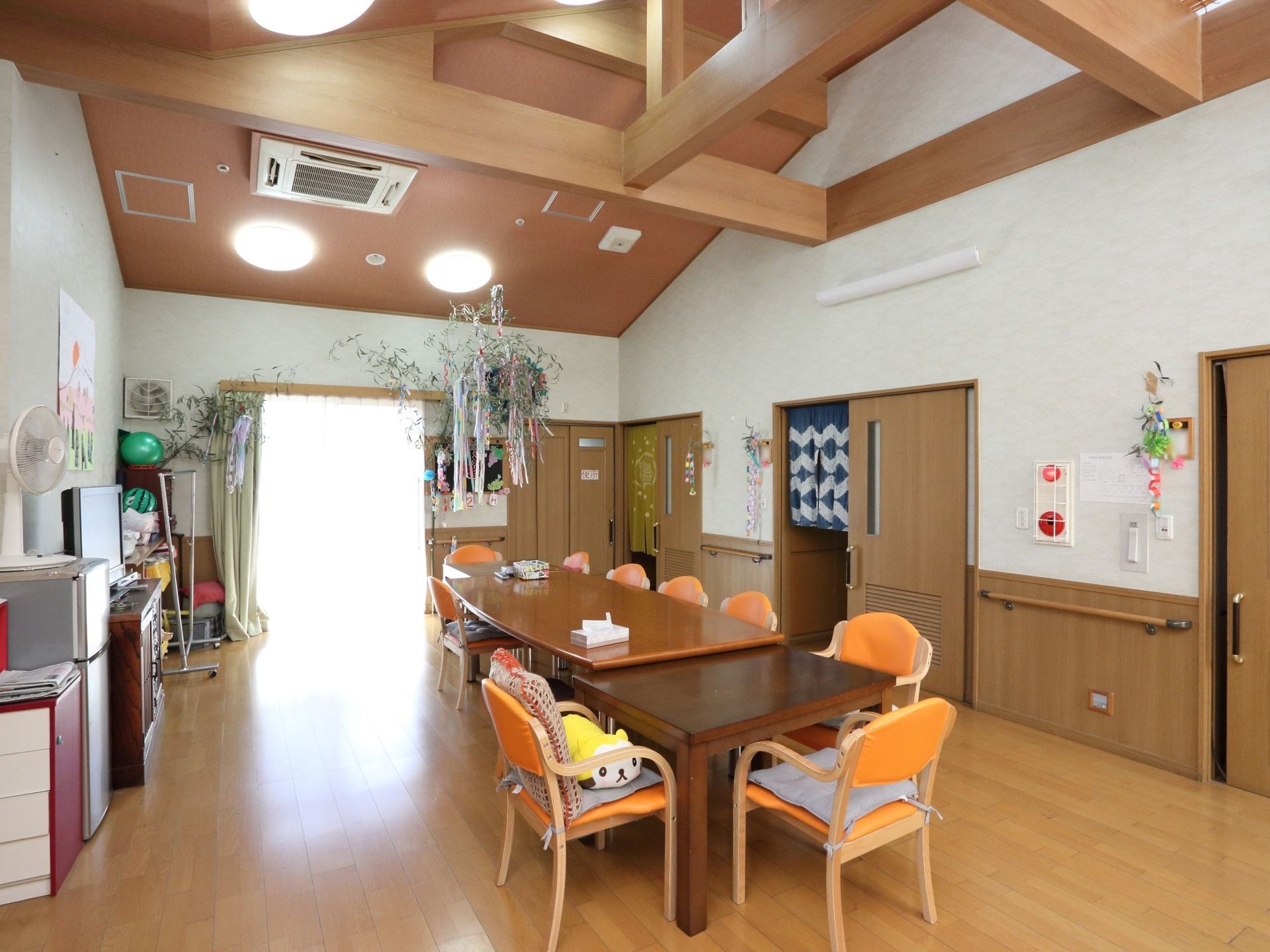 高い天井で明るさと伸びやかさを感じる空間の共有スペースである。真ん中にテーブルと椅子を配し、入居者様のくつろぎスペースとなっている。