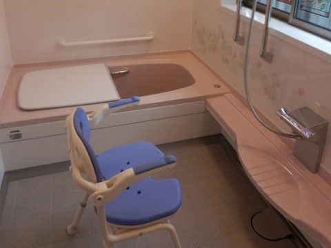 浴槽などは柔らかな色合いで、くつろいで入浴できる。浴槽は一人用になっている。滑りにくい介護用の椅子も置かれている。