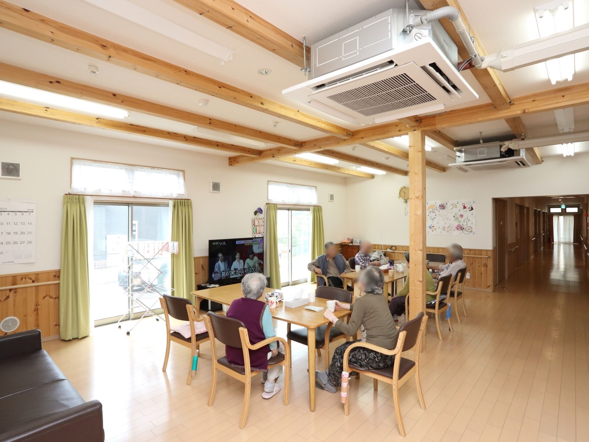 共有スペースには入居者様、皆さまが集ってテーブルの椅子に腰掛け、お茶を飲みながらテレビや談笑を楽しんでいる。