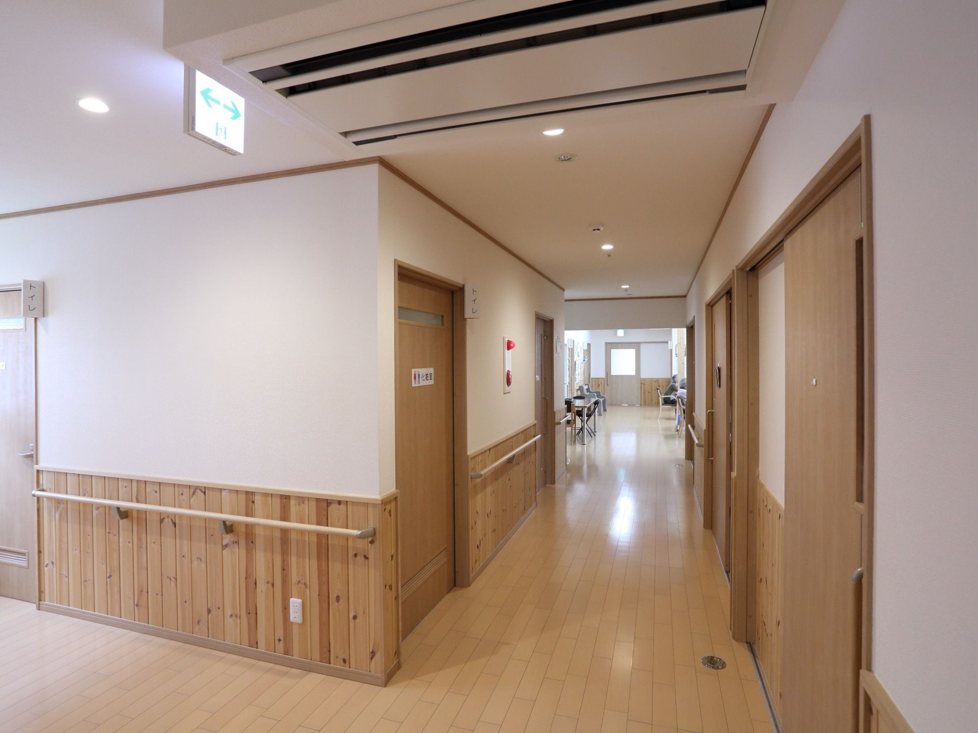 横幅のあるきれいなフローリングの廊下である。壁は腰高の位置まで木製の板張りとなっている。壁に沿って、手すりが設置されている。