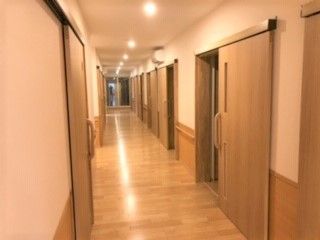 まっすぐな施設内の廊下とその両側についている個室のドア。引き戸仕様のドアがある様子