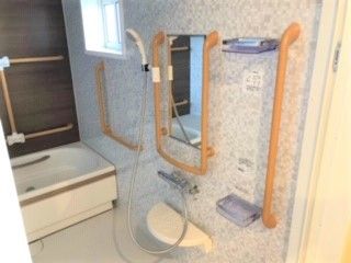 壁にまんべんなく手すりがついている施設の浴室の様子。鏡の周りにも手すりがある様子