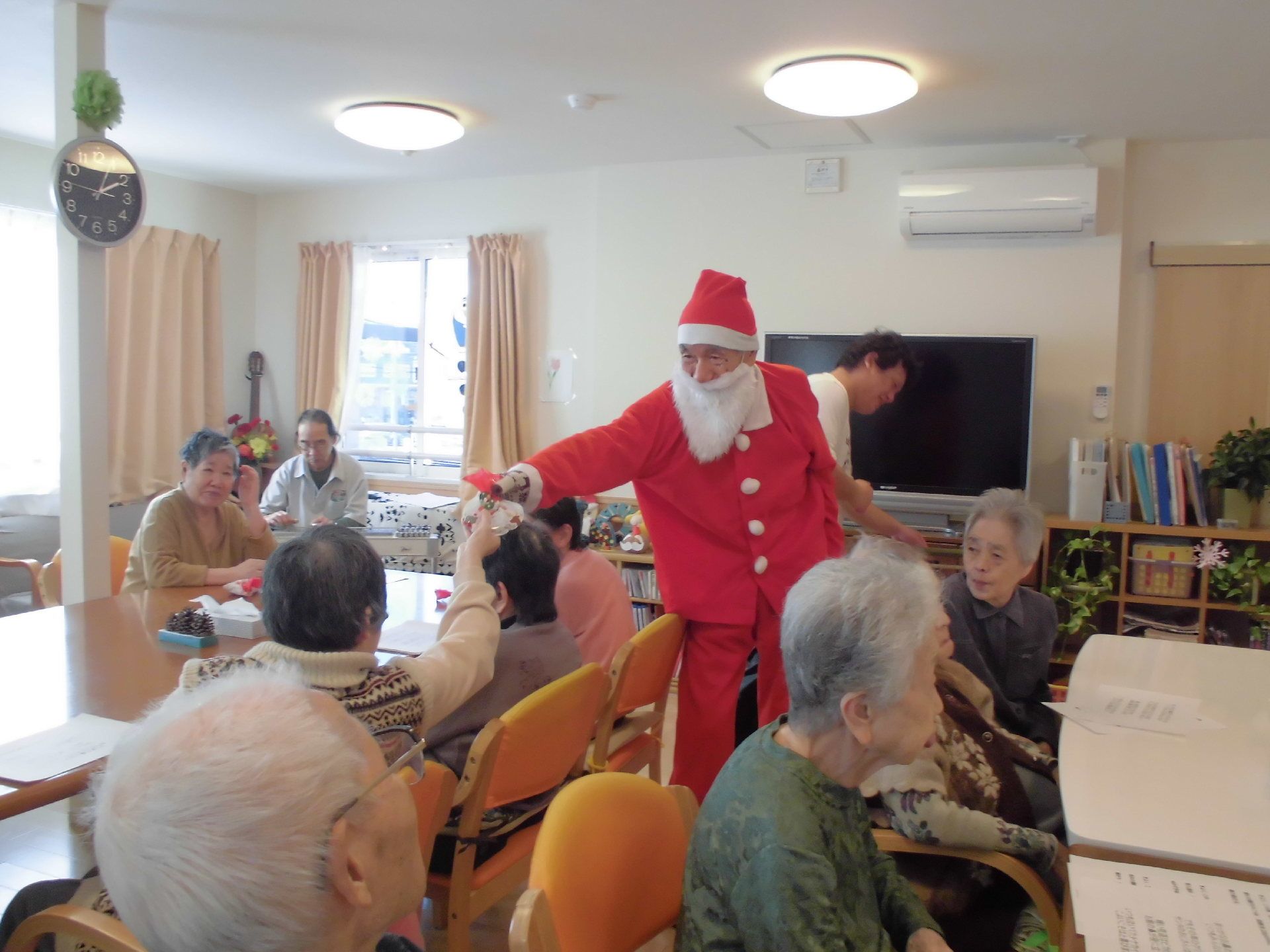 イベントでクリスマス会をしている様子。赤い衣装をまとったサンタクロースがプレゼントを配っている