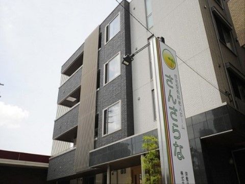 白と黒をベースにした高級感のある外壁で、エントランス横に看板が設置されている外観