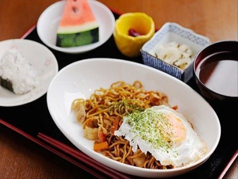 食事はメインの目玉焼きが乗った焼きそばに、おにぎり１つ、副菜が２品、お吸い物、デザートにはカットされたスイカが用意されている。