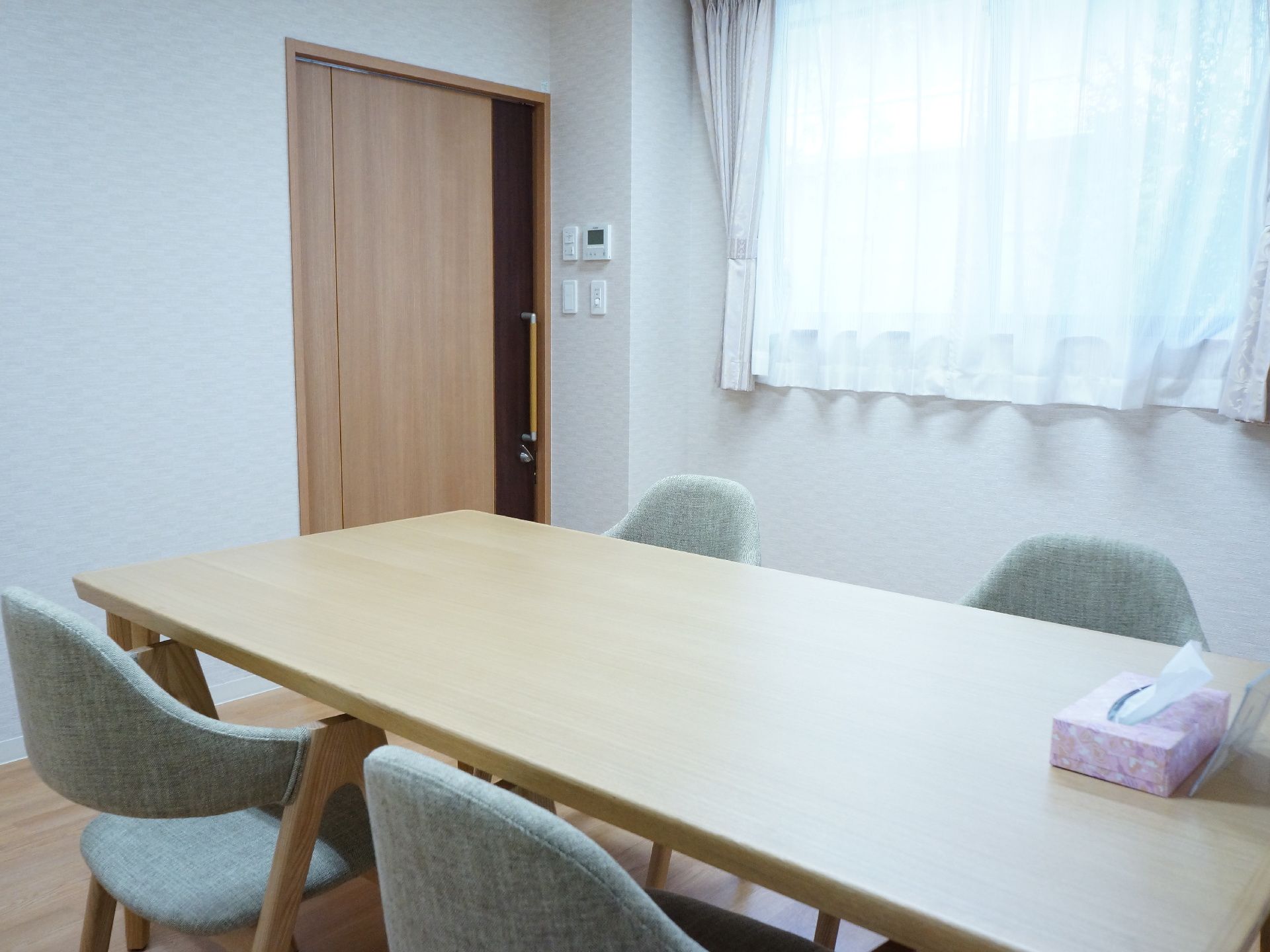 木目調の引き戸の出入口から中に入れば、白色の壁に木目調の床、横一面は窓。4人掛けのテーブルと椅子が置いてある。