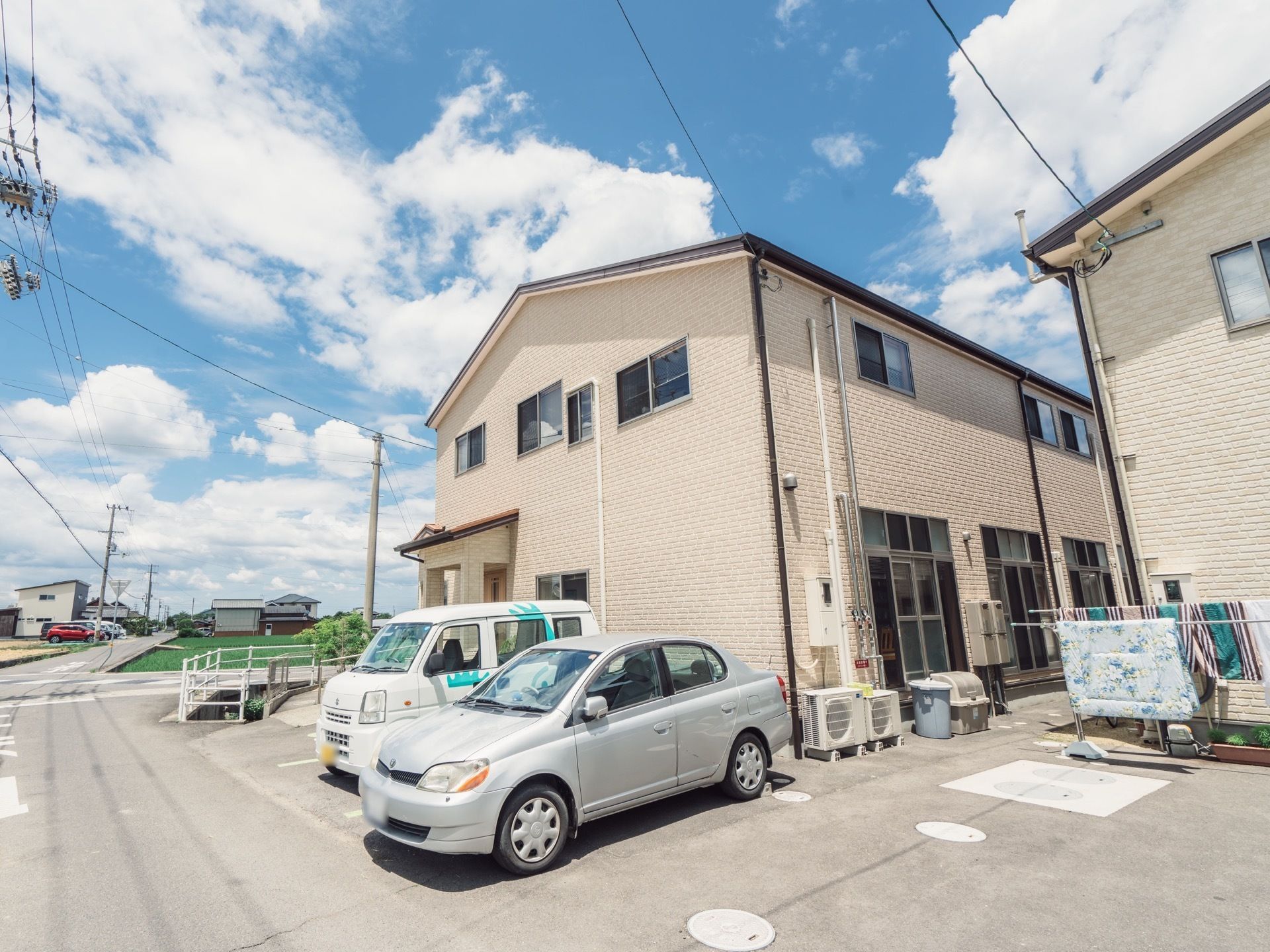 淡いピンクで統一された２階建ての建物である。エントランスの前に駐車スペースが完備されている。周辺は自然に恵まれた環境である。