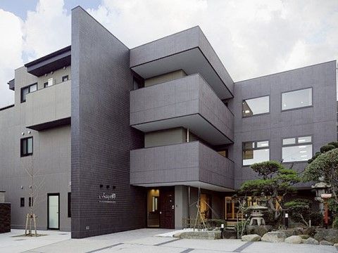 シンプルモダンな外観と石灯籠が置かれた和風庭園が対照的な正面玄関