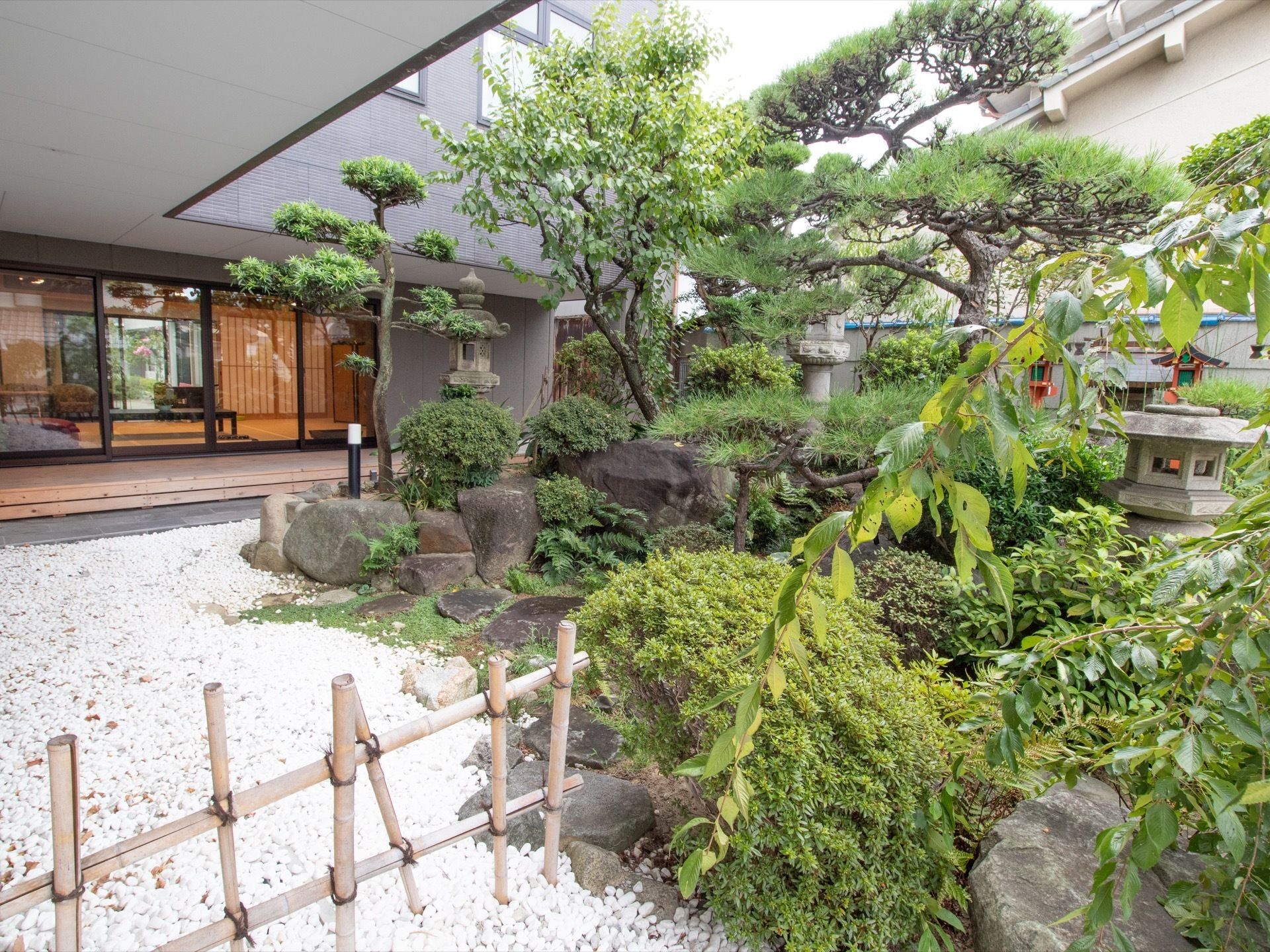 和室の共有スペースの窓からは、中庭を望める。日本庭園風の植栽が植えられている。竹の柵で区切られている。