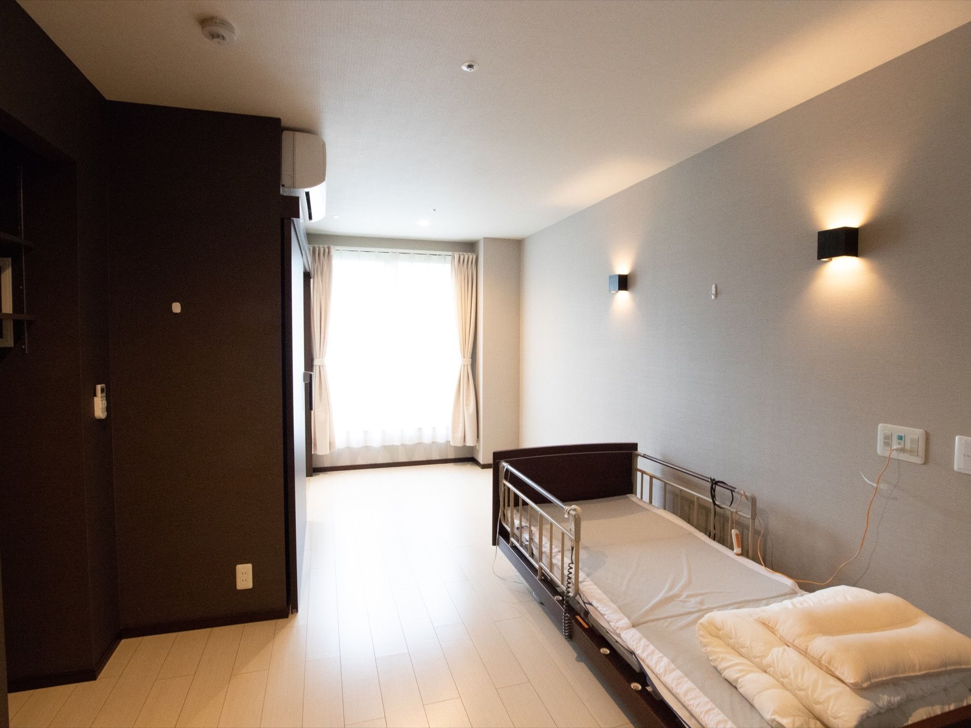 落ち着きのあるブラウンカラーのワンルームになっている。部屋には介護用ベットが置かれており、布団も用意されている。