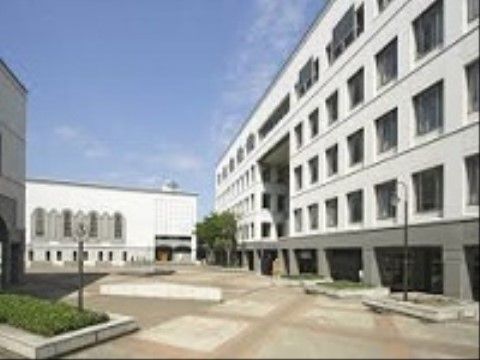 施設の近くには大学がある。白を基調とした建物が並んでおり、たくさんの窓がある。街灯が備え付けられている。