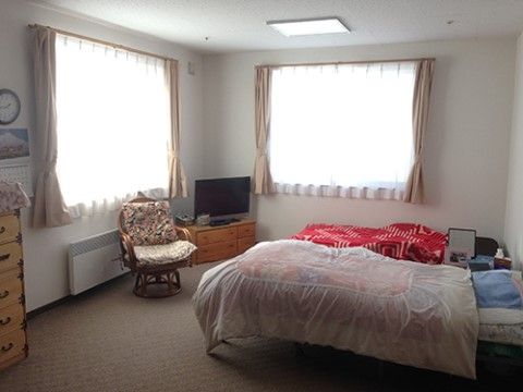 ２面に窓がある部屋に、ベッドが２台並んでいる。角にはテレビが置かれ、窓の並びには整理ダンスも見える。