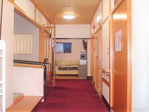 えんじ色の床になっている明るい廊下である。手すりを設置しており、安全に移動することができる。奥にはソファを設置している。