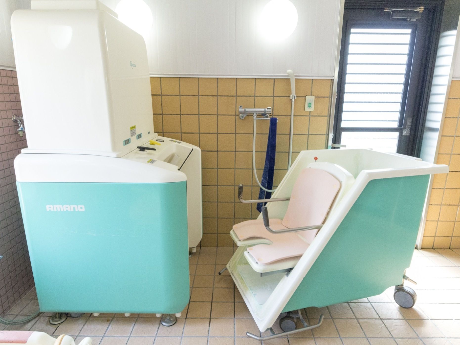 特殊浴槽の設備が整っていて、座位のままで入浴ができるようになっている。壁にナースコールが設置されている。
