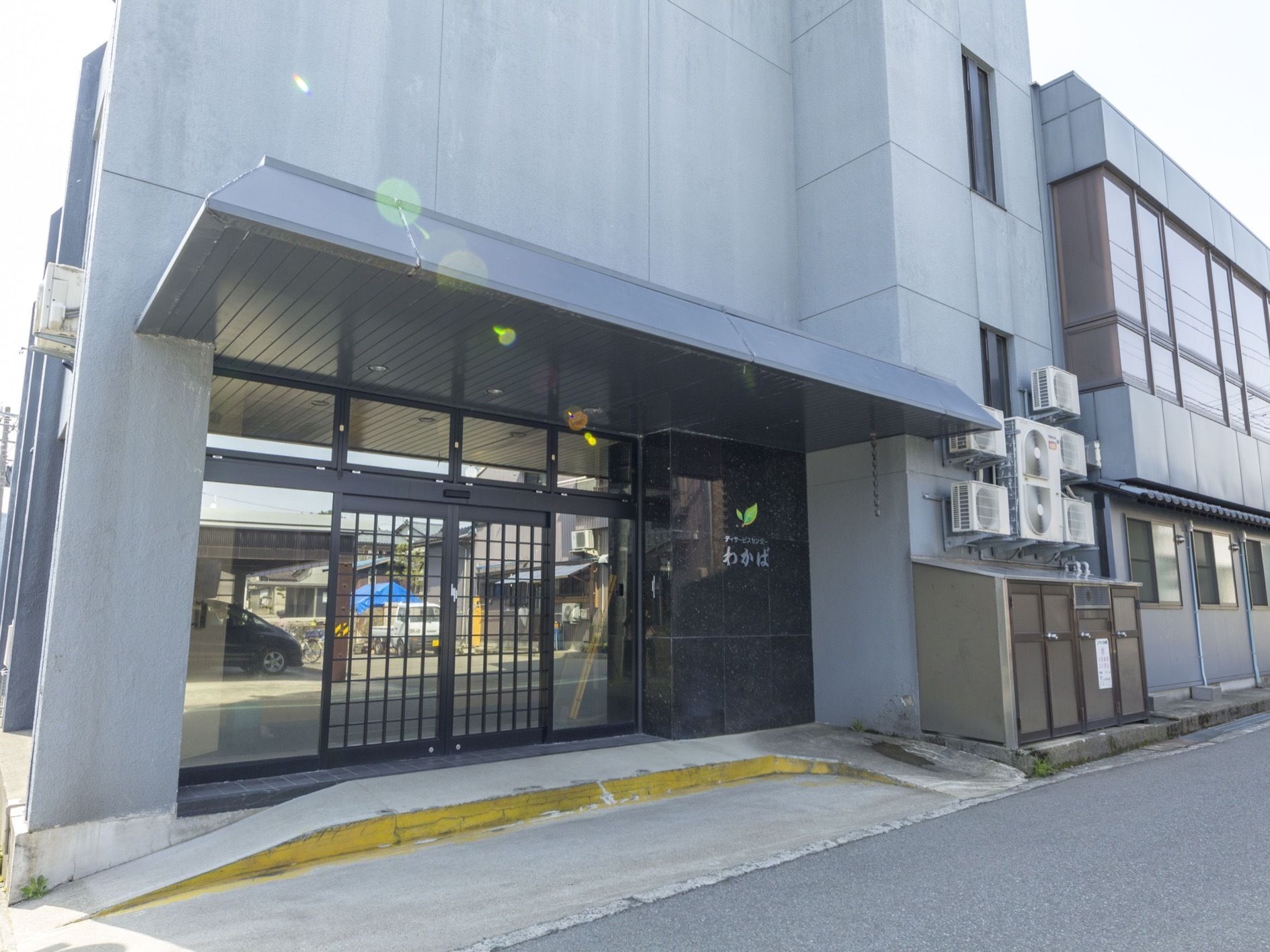 黒い外壁の建物で3階建てになっている。ガラスが使われた自動ドアの玄関で、安全に出入りすることができる。