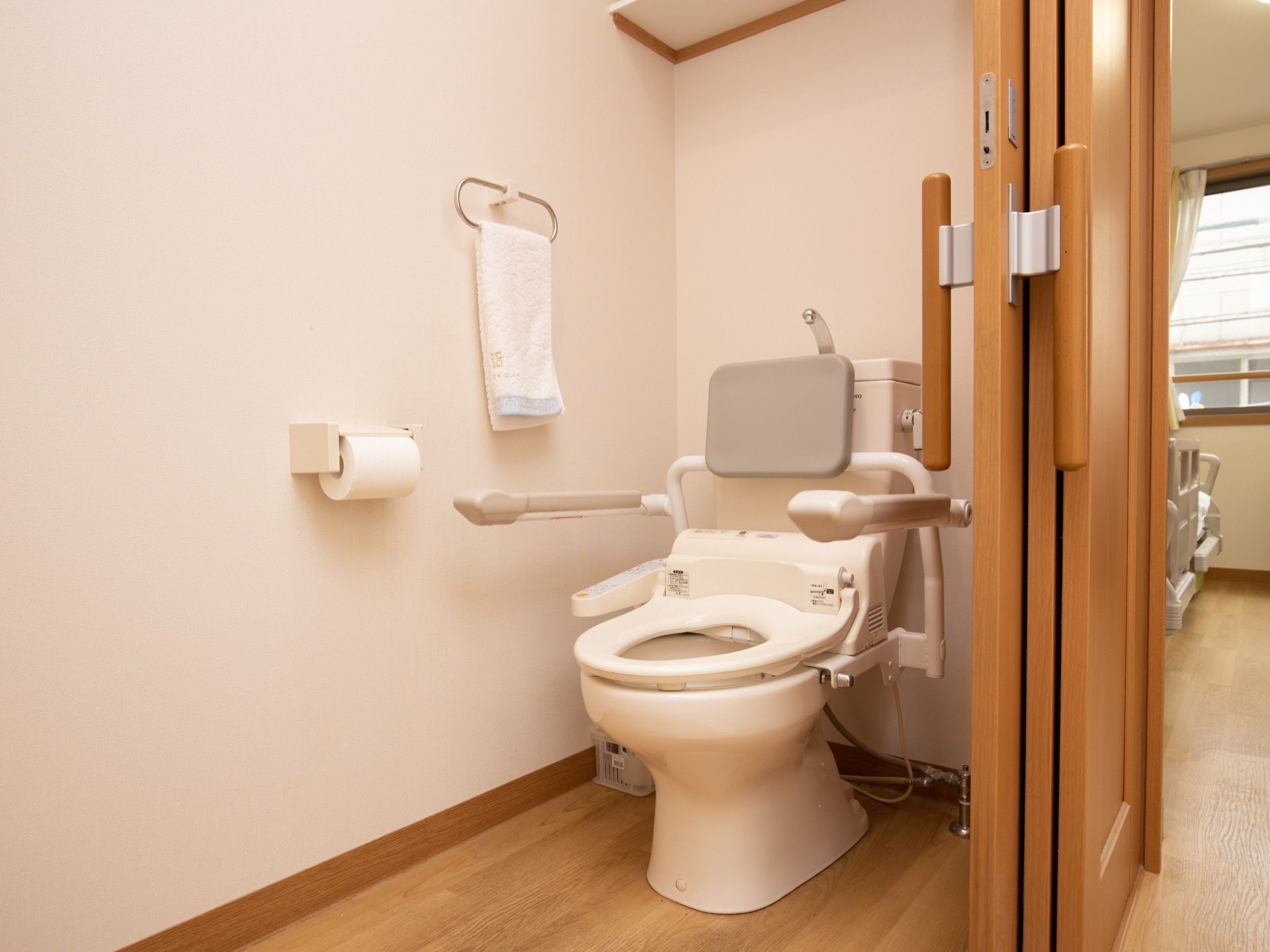居室のトイレは個室になっている。便座には蓋はなく、クッション性のある背もたれとひじ掛けが取りつけられている。