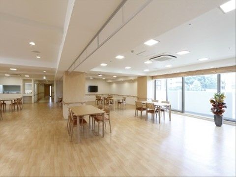 広々としたスペースの床には間隔をあけてテーブルセットが置かれている。広い窓があり、壁には手すりが設置されている。