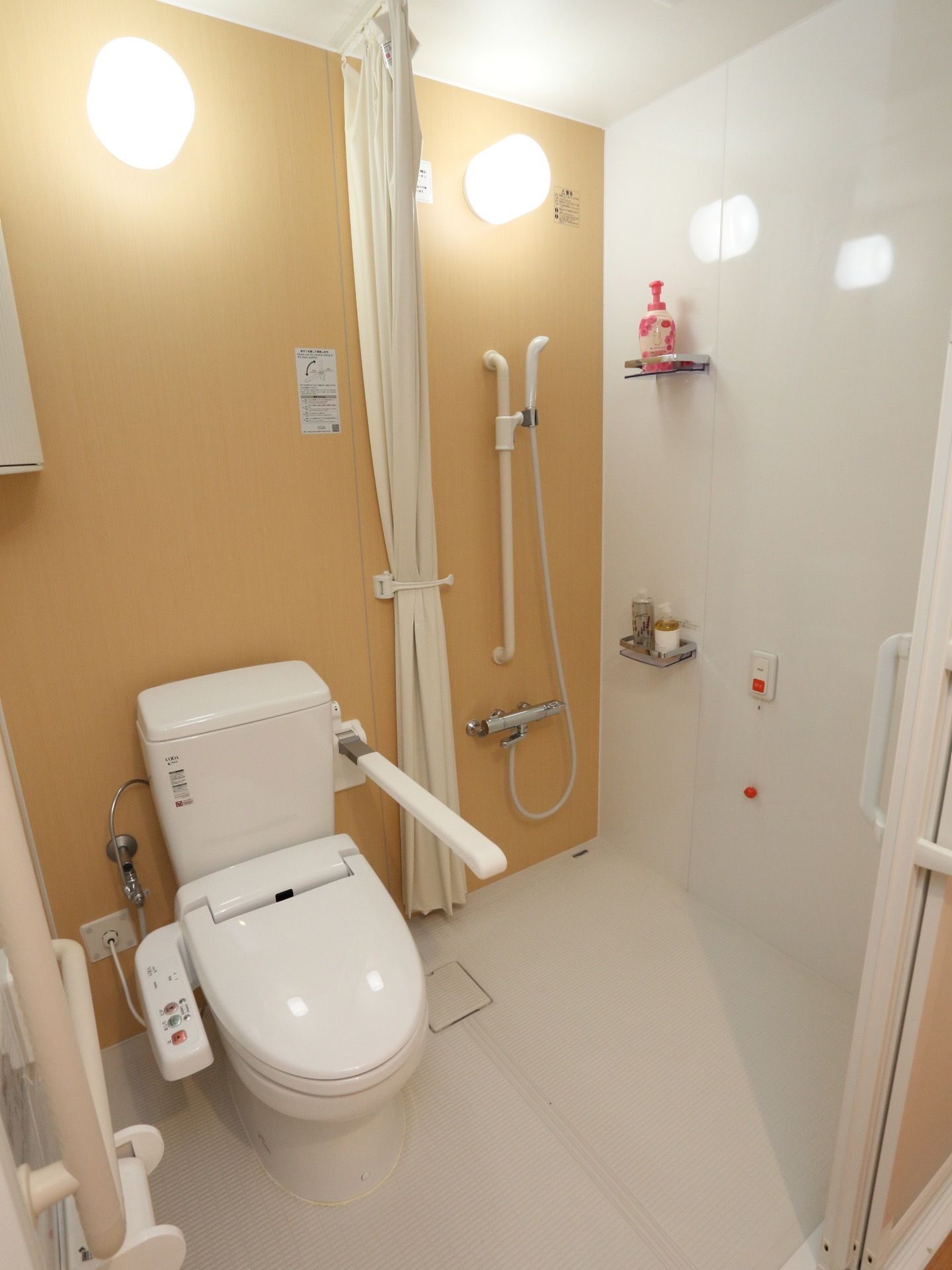 シャワーが隣接したトイレスペースである。それぞれの上部には照明を設置している。壁際には手すりやナースコールを取り付けている。