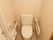 白色の壁に囲まれたトイレスペースである。便器の両側には手すりを設けており、壁際にはナースコールを取り付けている。