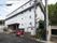 白とダークブラウンのツートーンカラーを用いた、４階建ての建物。玄関前には階段があり、手すりが設置されている。