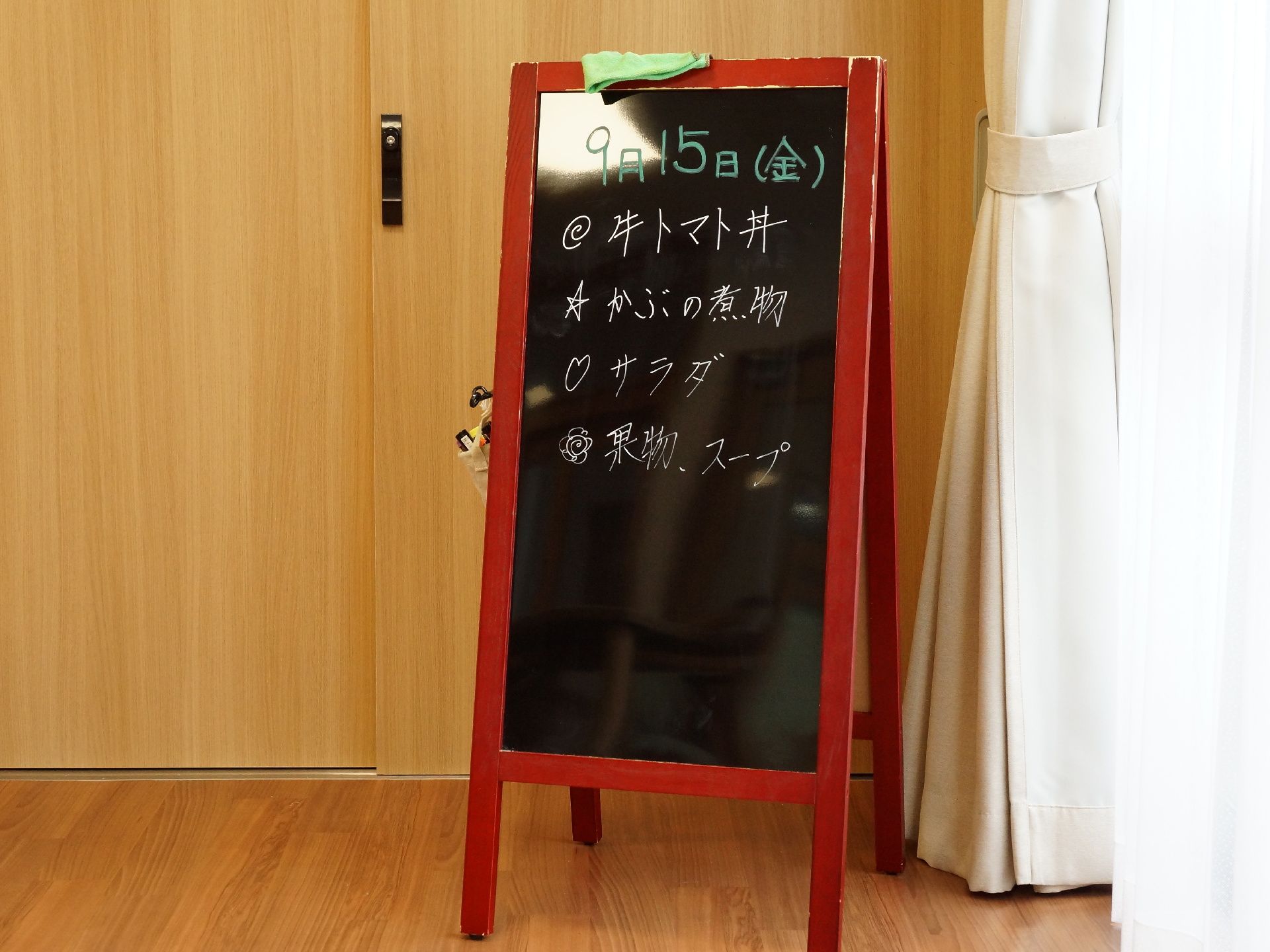 リビングには窓際に木製のメニューボードが置かれている。黒地に緑色の文字で日付、白い文字で献立が記入されている。