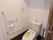 スライドドアの設置された個室のシャワー付きトイレである。利用する際の右側にL字型の手すりがある。ナースコールも完備。