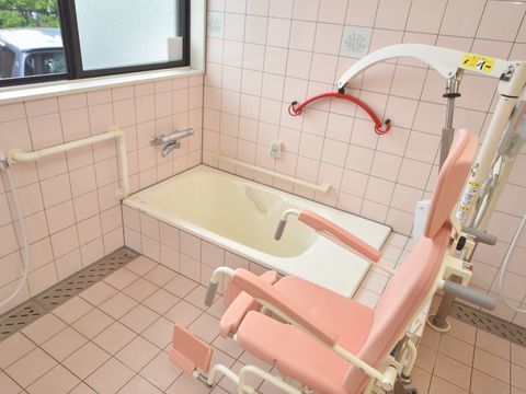 介助用の椅子と器具の設置、壁に手すりのされた、窓のある浴室