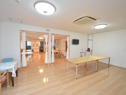 部屋をカーテンで仕切った、白い壁の広い多目的スペース