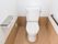 白い洋式便器が完備されているトイレである。壁には、コンセントやペーパーホルダー、手すりがある。