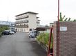 門壁が完備された施設である。敷地内に屋根付き駐輪場や駐車場が設置され、奥に４階建ての施設が立地している。