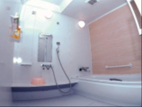 白いユニットバスが完備されたシンプルなデザインの浴室である。安全に入浴していただけるよう、手すりが設置されている。