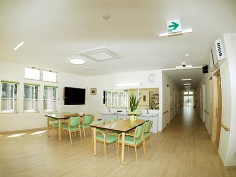 床が木目調になっている、落ち着いた雰囲気のリビングである。大きなテレビが設置されており、洗面台が複数ある。
