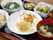 トレーの上に炊き込みご飯とお味噌汁、メインおかずに小鉢が3つ、そしてお茶が添えられてセットされている。