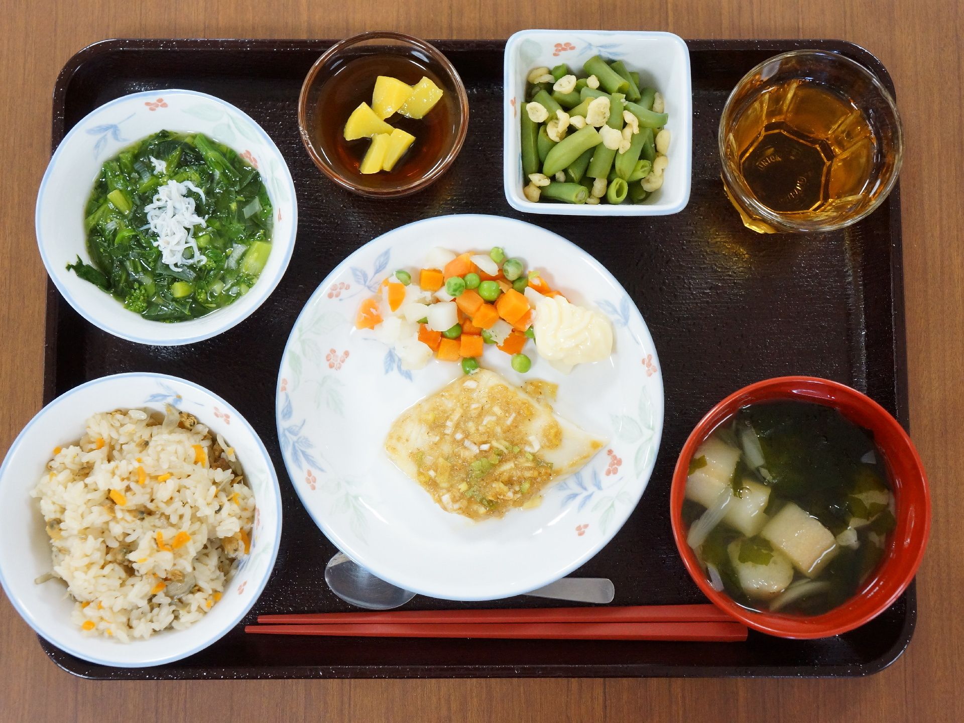中央にメインおかず、ご飯と汁物、小鉢が3つにお茶が添えられた1食の食事である。栄養バランスと品数、彩りに配慮された献立である。