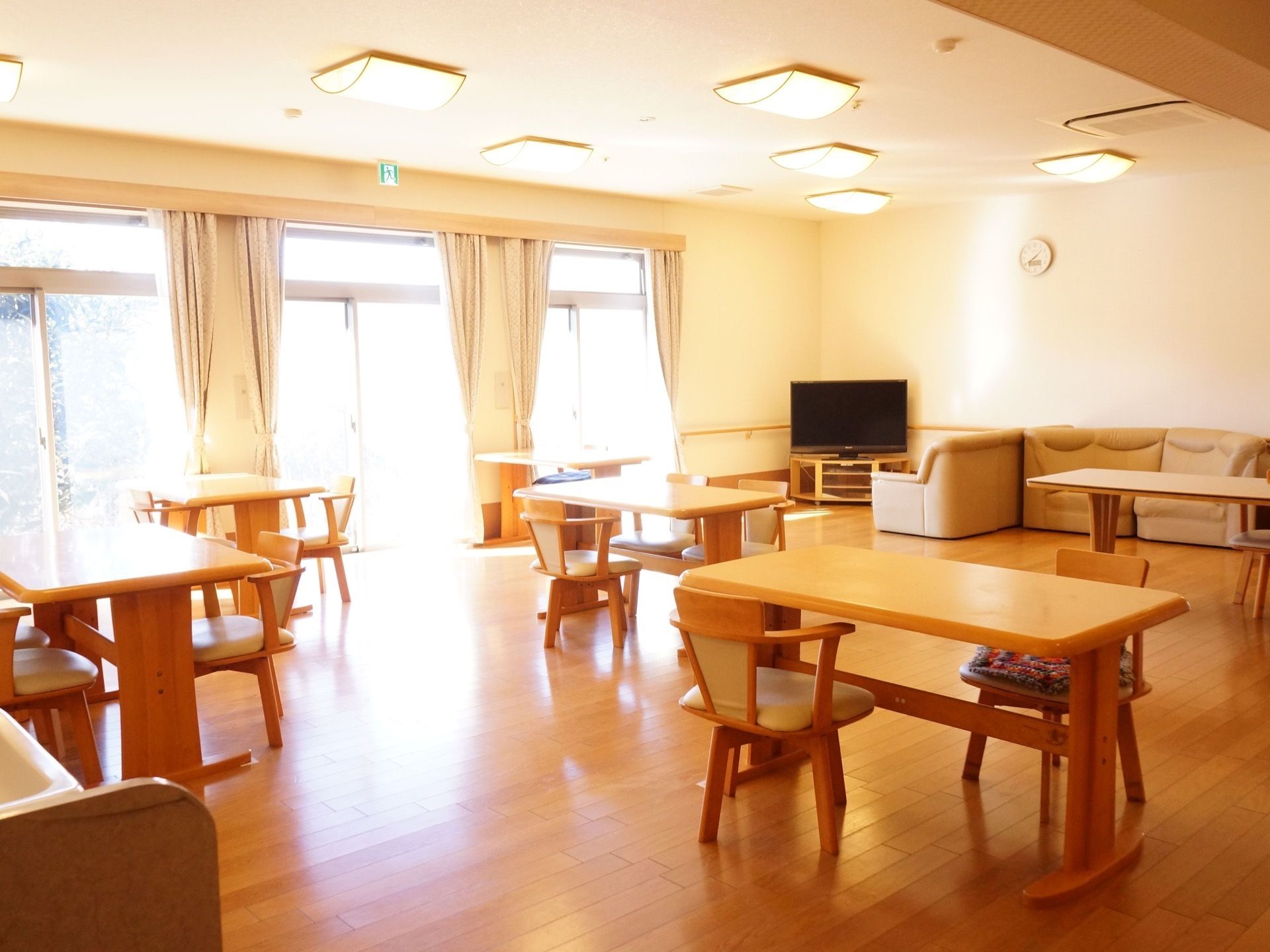 食堂は壁の一面がほぼ窓であり、外から明るい光が差し込んでいる。温かみある木製のテーブルや椅子が規則的に並べられている。