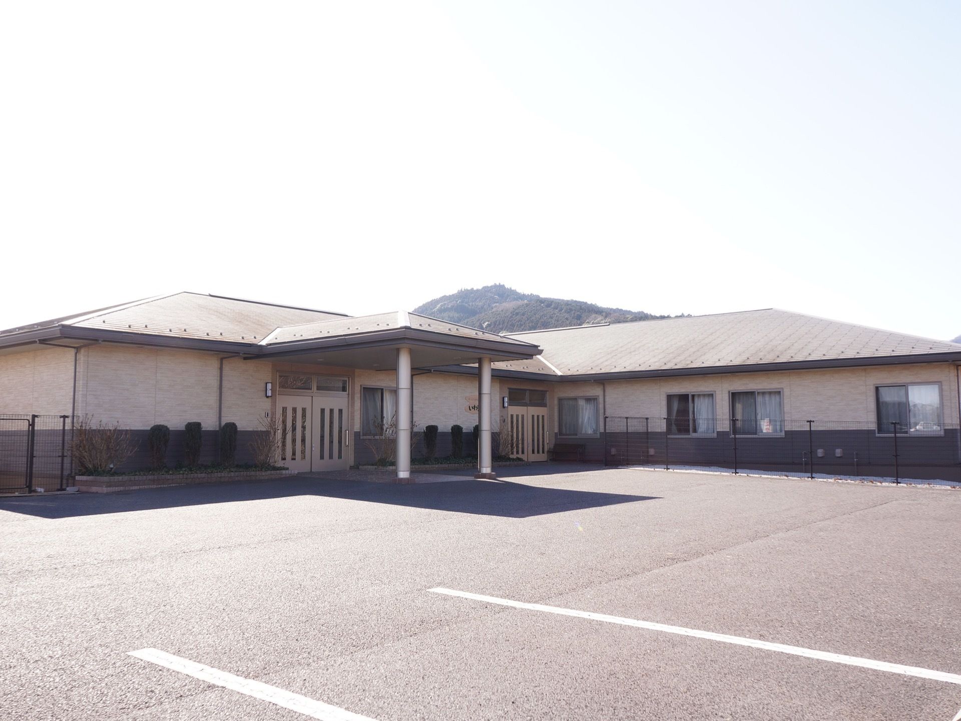 施設は舗装された広い敷地の中に建つ平屋建てである。周辺にも高い建物はなく、太陽の明るい日射しが降り注いでいる。