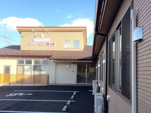 明色系にデザインされた外観でかわいい雰囲気である。２階の外壁に赤文字で施設名が描かれている。建物の前に駐車場を完備。