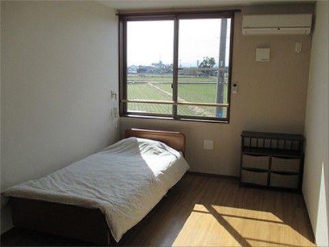 窓に手すりが備え付けられ、居室から外をゆったり眺めることができる。エアコンとベッド、収納家具が備え付けられている。