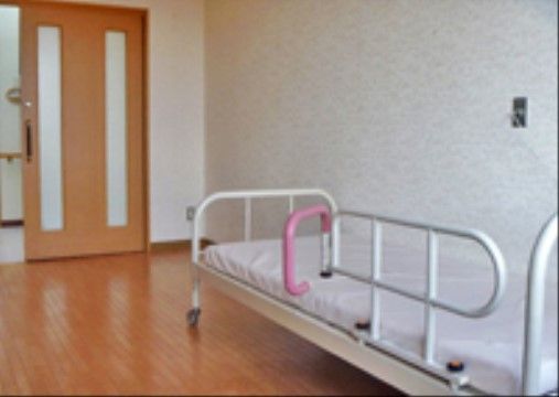 居室の引き戸を開けるとすぐに、ベッドが置いてある。ベッドには、Ｌ字に動かすことができるベッド柵が付いている。