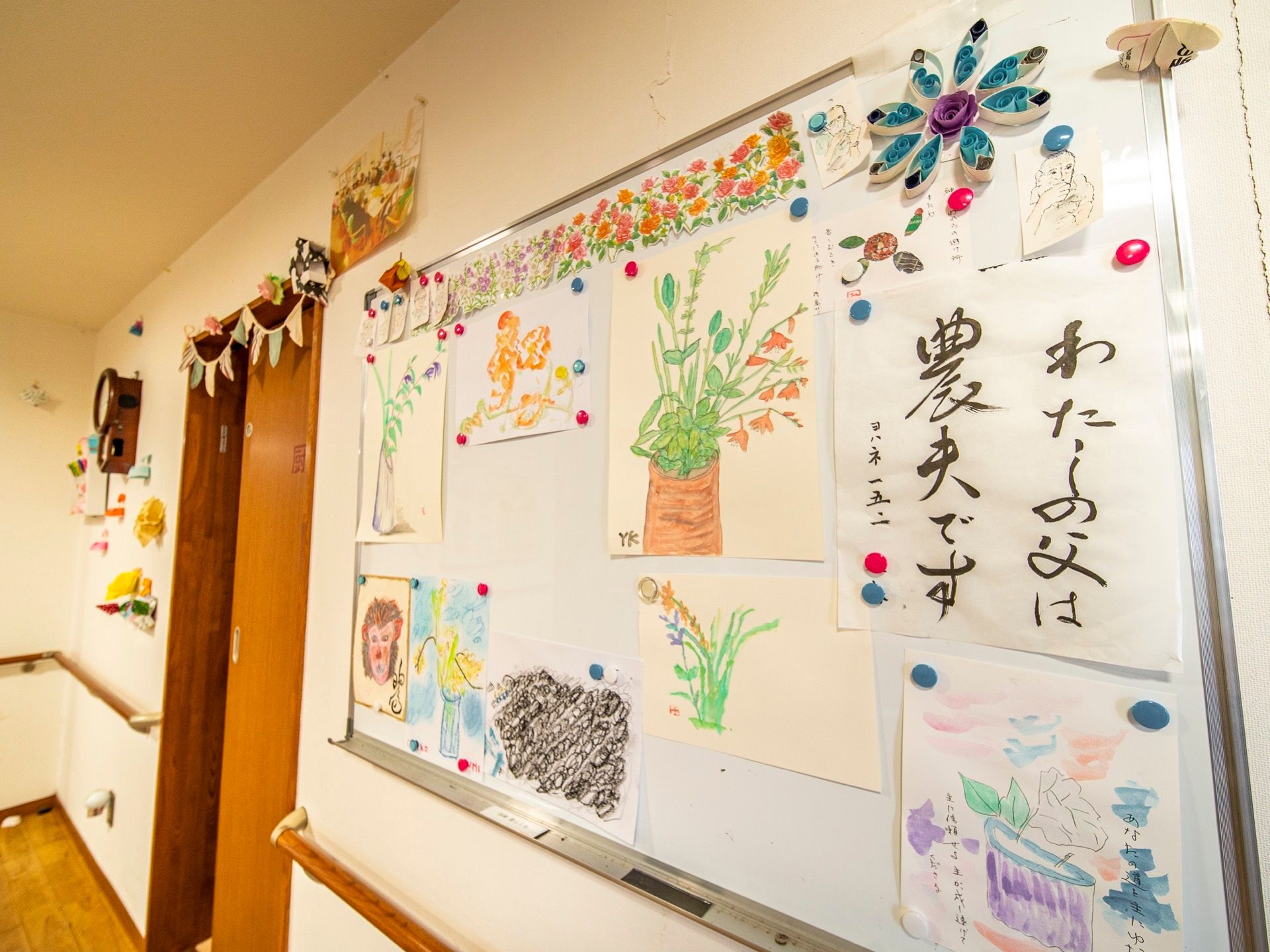 廊下の壁にボードを掛けて、絵画や書道の作品を貼っている。ドアの上部などに、手作りのレイアウトを取り入れている。