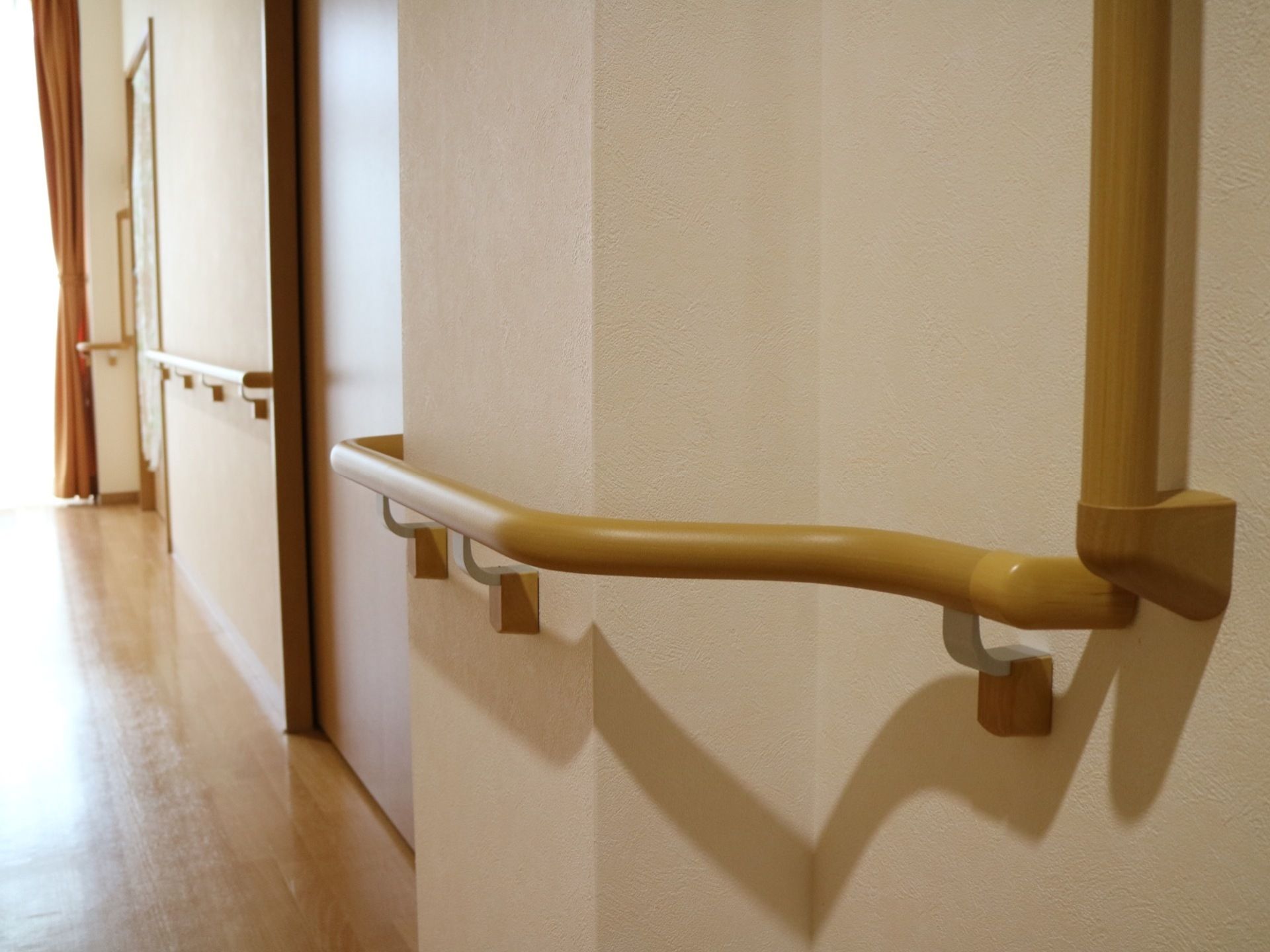 廊下の居室入口以外の壁に手すりが設置されている。壁の出っ張り部分の手すりは、ゆるやかに湾曲してつながっている。