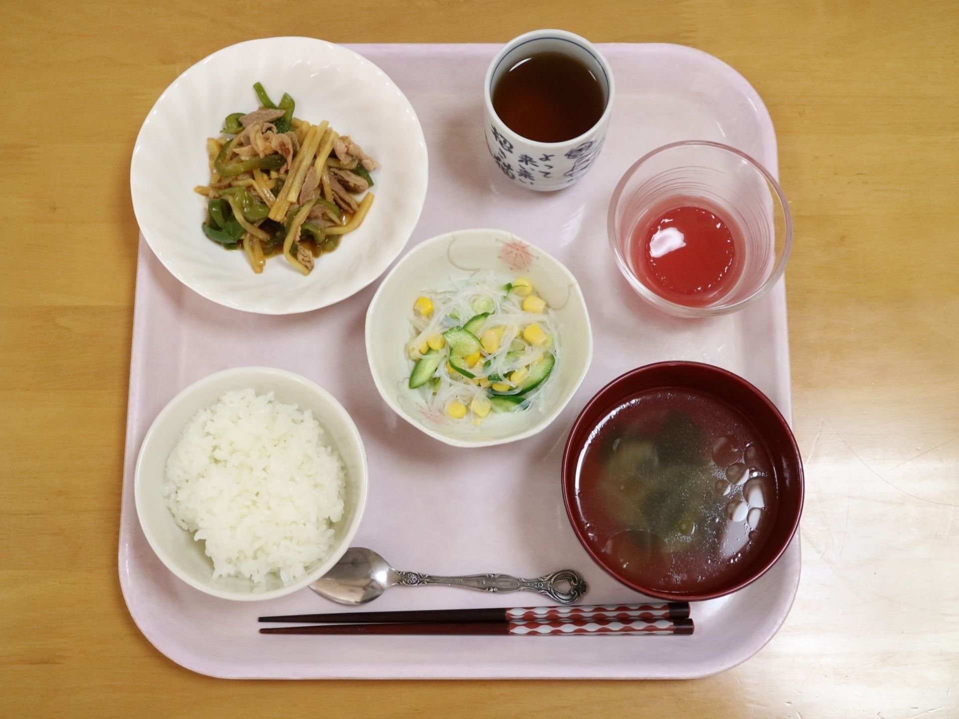 ご飯とみそ汁の他に、サラダやおかずが入った小鉢がピンク色のプレートに載っている。箸とスプーンが手前に置かれている。