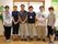 女性スタッフ４名と男性スタッフ２名が、受付前で横一列に並んで写真に収まっている。名札を下げているスタッフもいる。