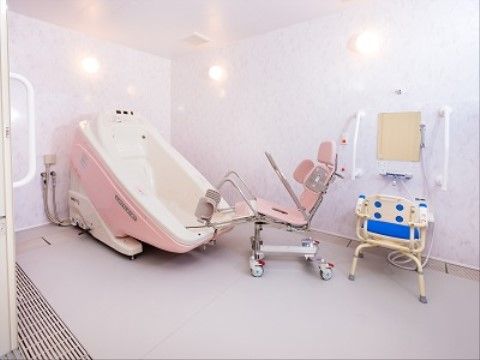 真っ白で清潔感のある浴室である。機械浴槽を完備しており、車椅子に乗った状態で湯船に浸かることができる。
