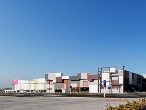 白い建物の左上に店舗のロゴがある大型ショッピングセンター。敷地の右側には外壁がモザイク模様のような建物があり、多くの専門店が入っている。
