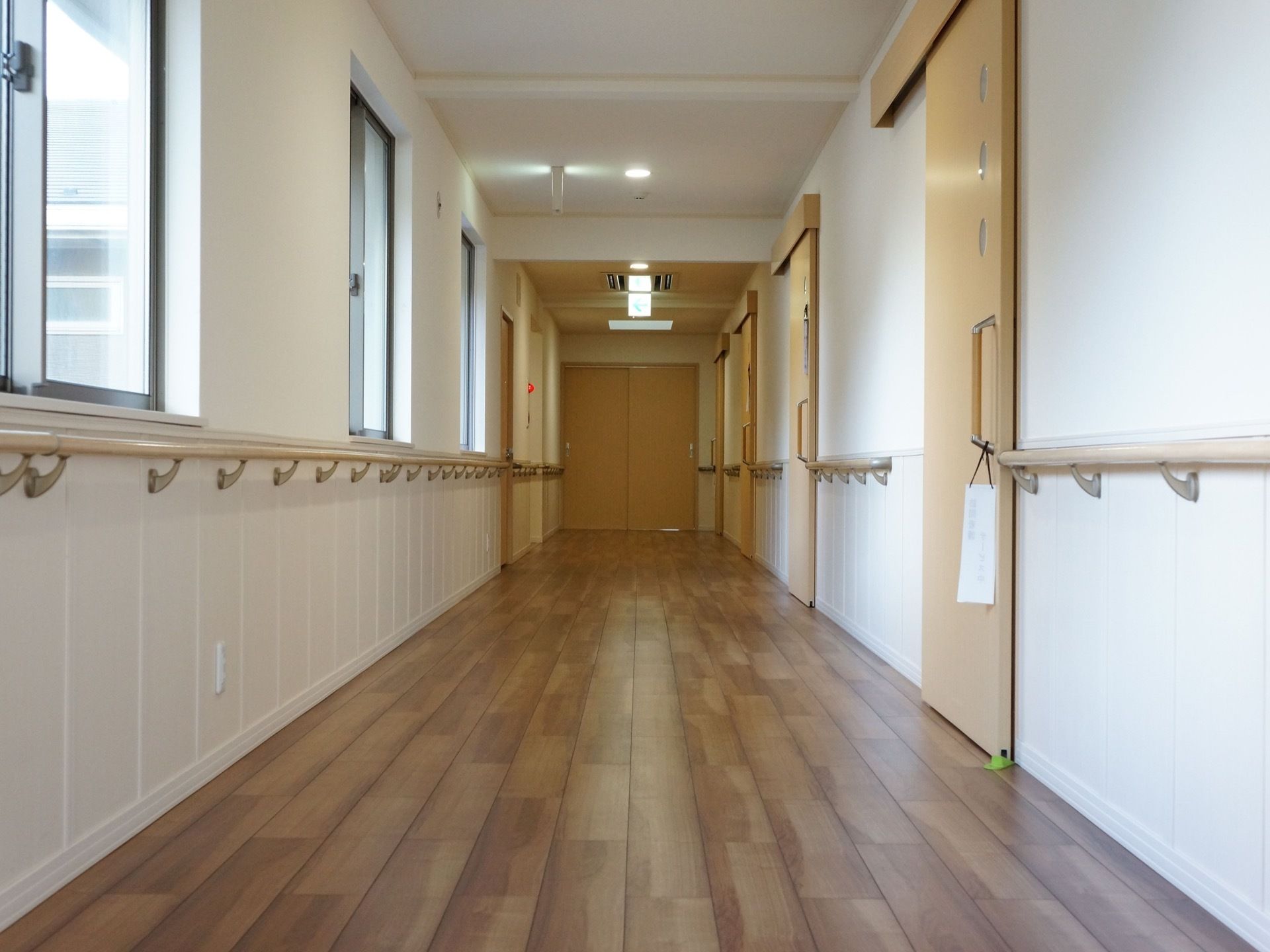 廊下の壁に手すりが取り付けてある。しっかり支えて移動することができる。引き戸の居室は開け閉めしても通行者にぶつかる心配はないので安全。