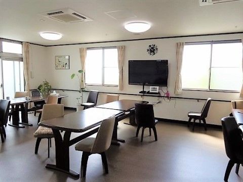 大きなテレビが設置された、明るい多目的室。机を広く使えるため、隣の人を気にせずにゆっくりとお食事やおしゃべりを楽しむことができる。