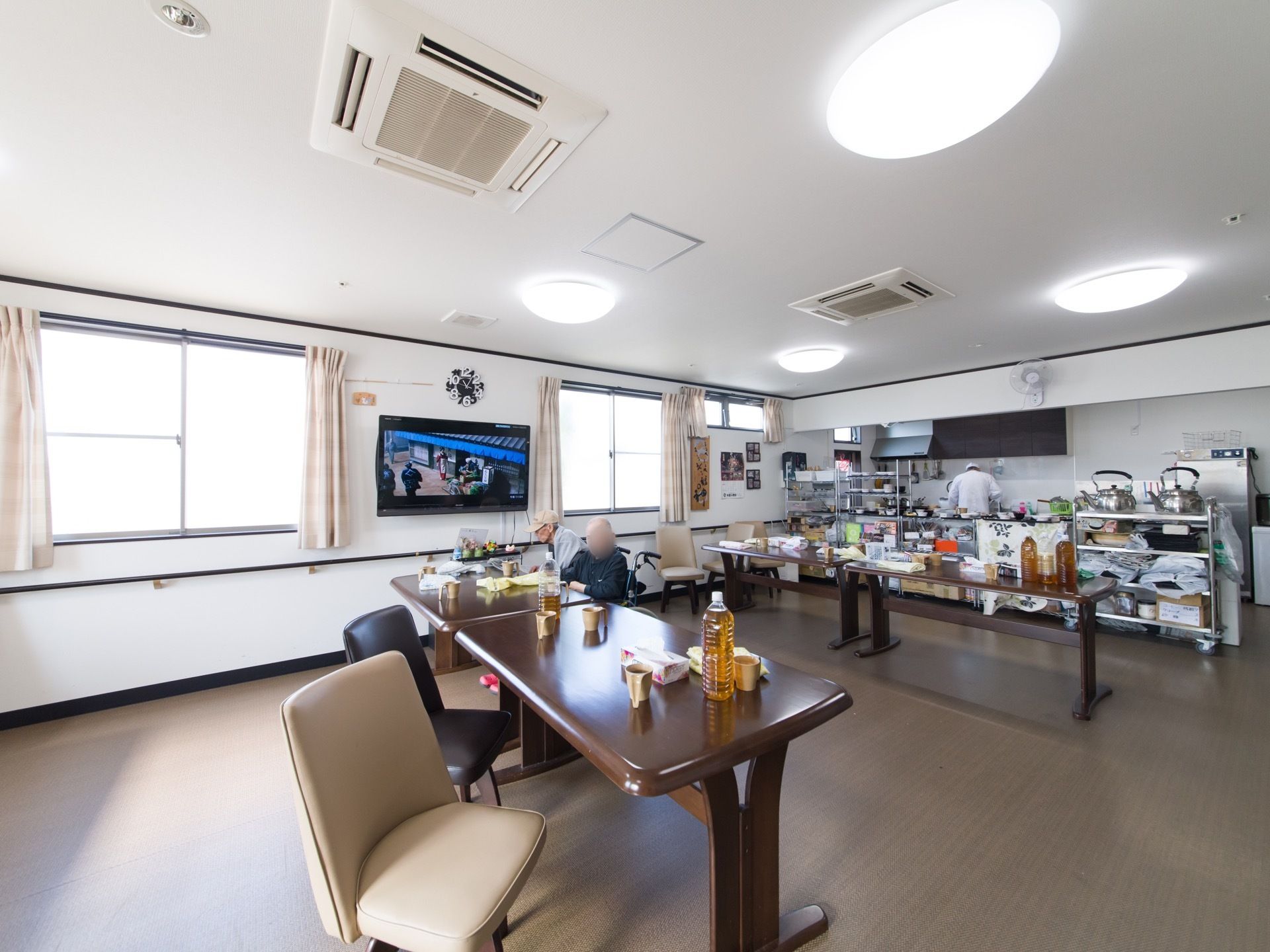 開放的で光が良く入る食堂では、入居者様が自由に好きな時間を過ごすことができる。テーブルの上にお茶などが置かれている。